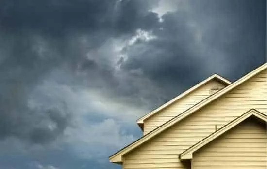 A painted home exterior with a storm front moving in behind it