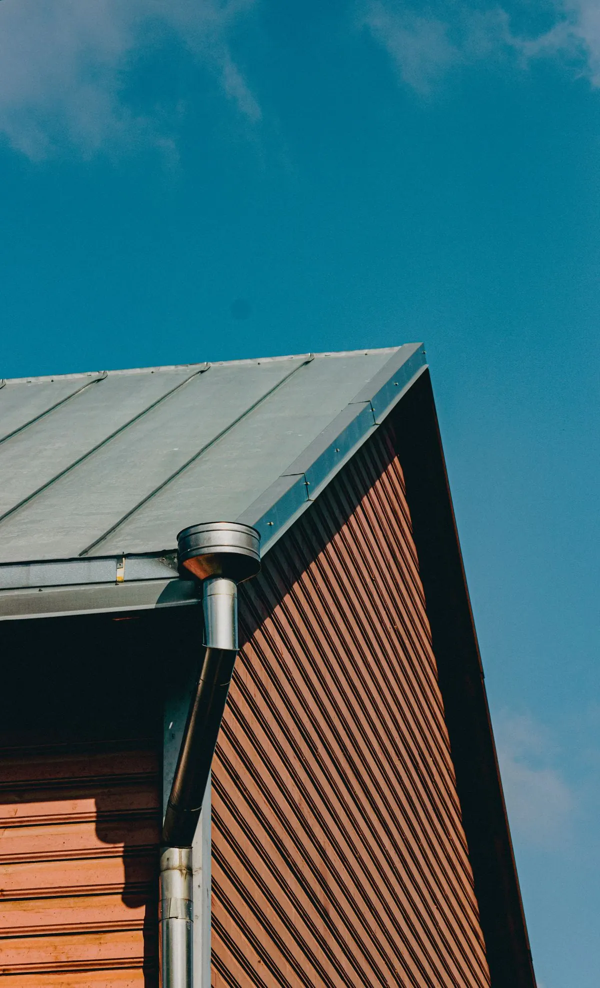 Close detail of a gutter outlet feeding into a downspout at a roof corner