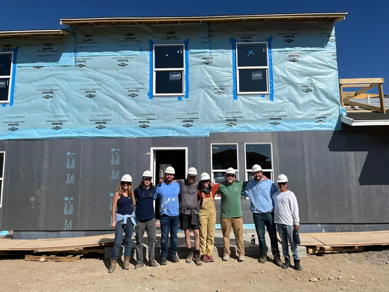 Kind Home Painting volunteers in hard hats outside a framed house at a Habitat For Humanity build in the Denver metro