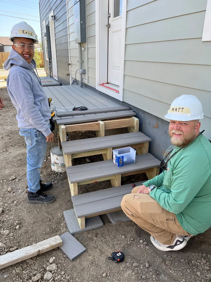 Two Kind Home Painting volunteers beside newly built porch steps at a Habitat For Humanity build