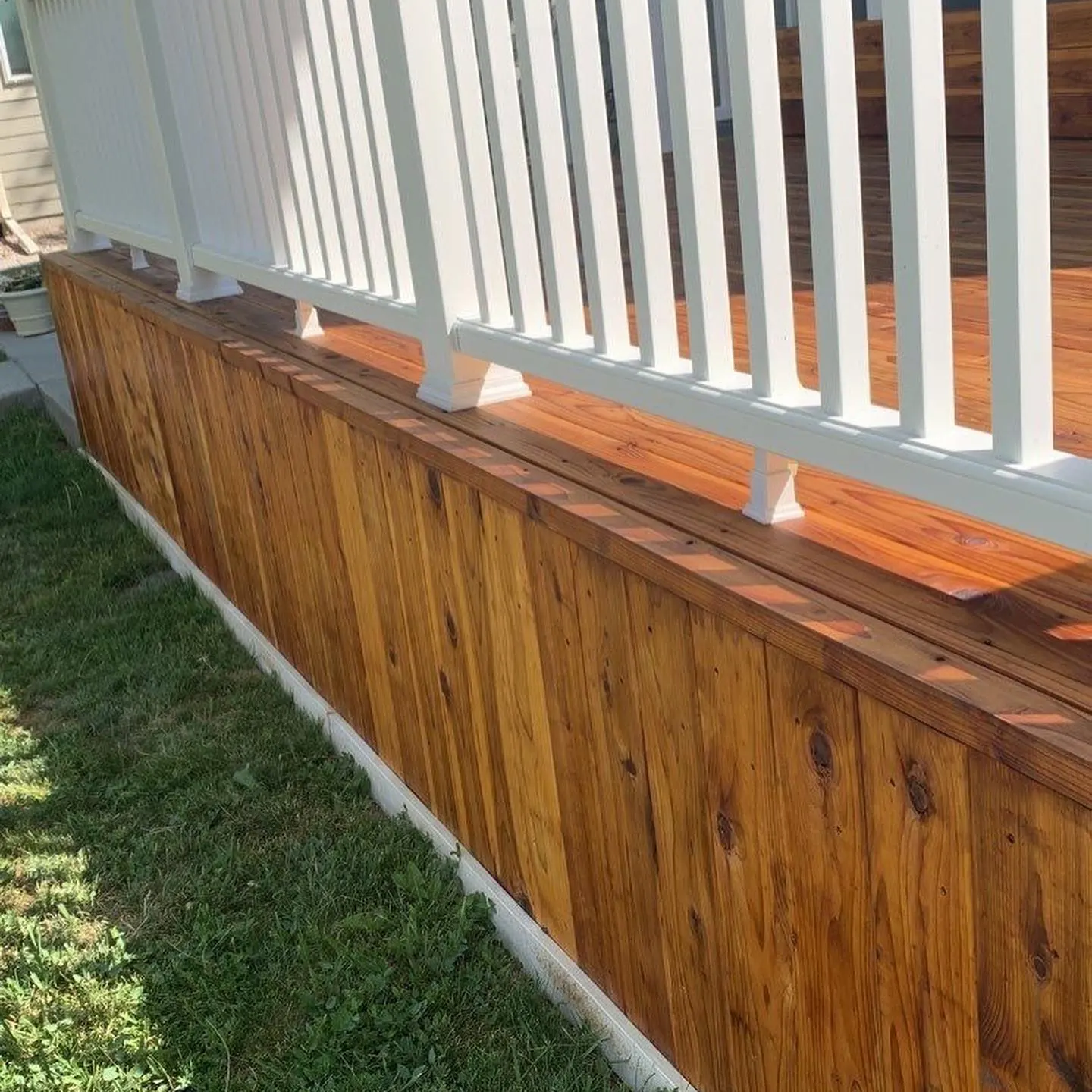 Freshly stained redwood deck skirting and railing cap, stained to full saturation